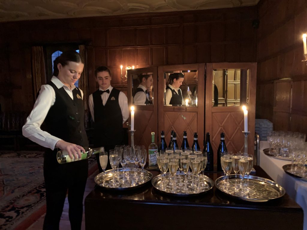 St John's College catering staff pouring drinks by candlelight in the Old Combination Room.