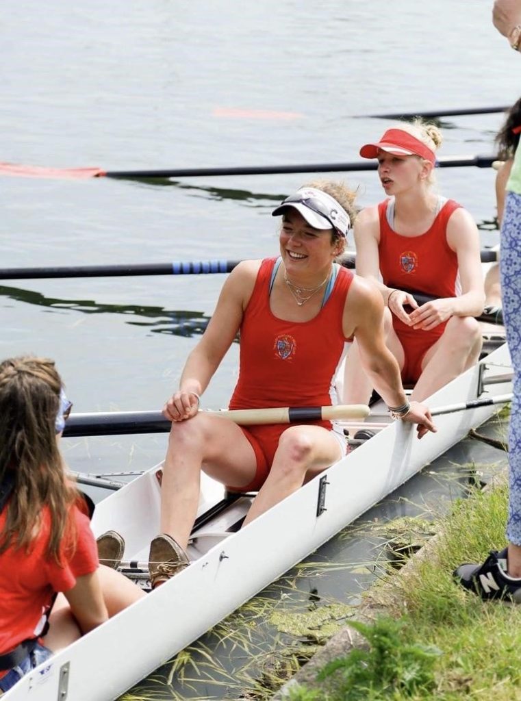 Fiona is in a rowing boat wearing a red uni-suit.