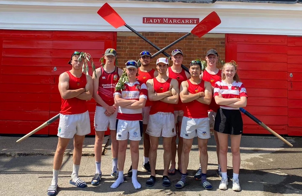 The rugby team/M4 stand outside of the Lady Margaret Boat House. Their blads are beind them.