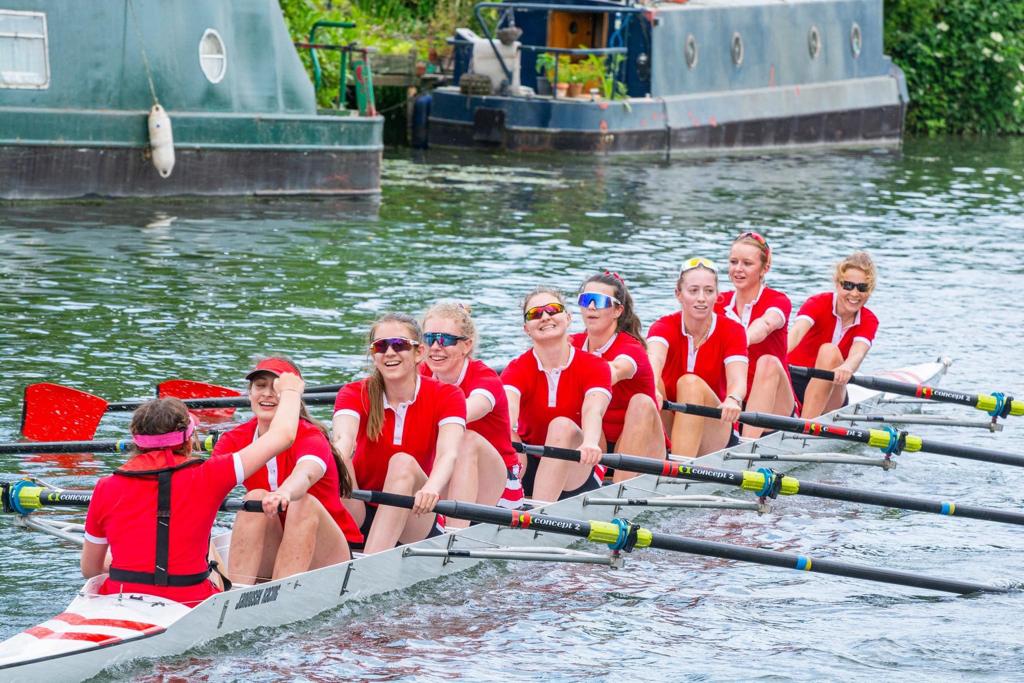 W2 completing its race. The rowers are wearing red shirts with white piping. They all look pleased and relieved.