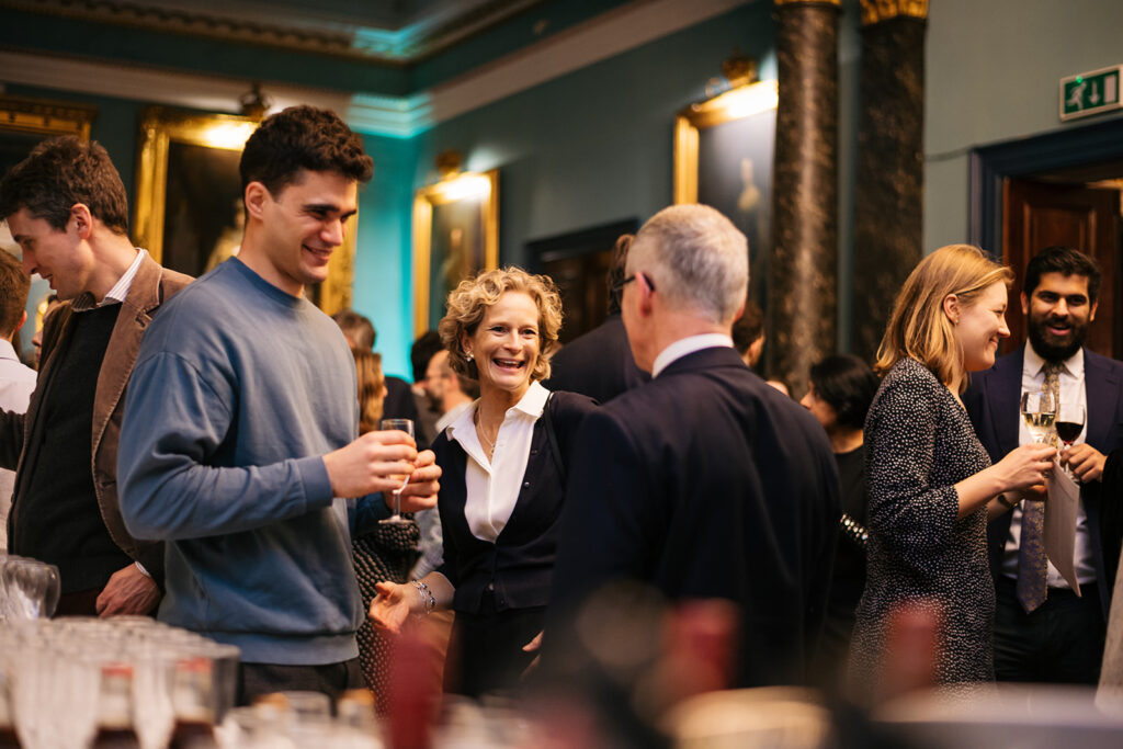 An image from London Christmas drinks. Alumni stand together smiling and laughing.