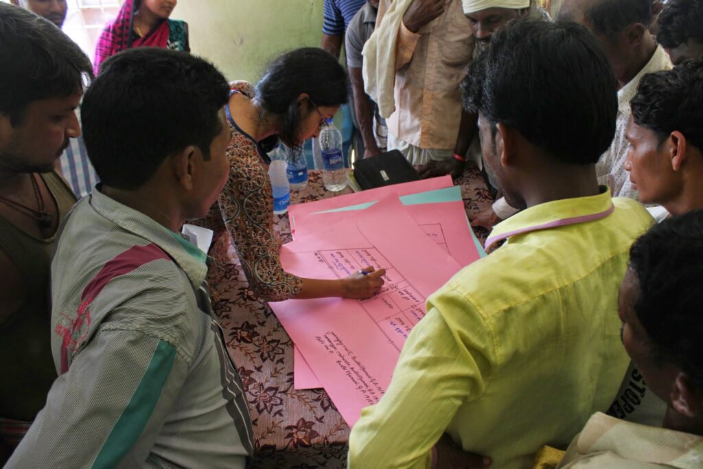 Prachi writes on a large pink piece of paper while others gather around