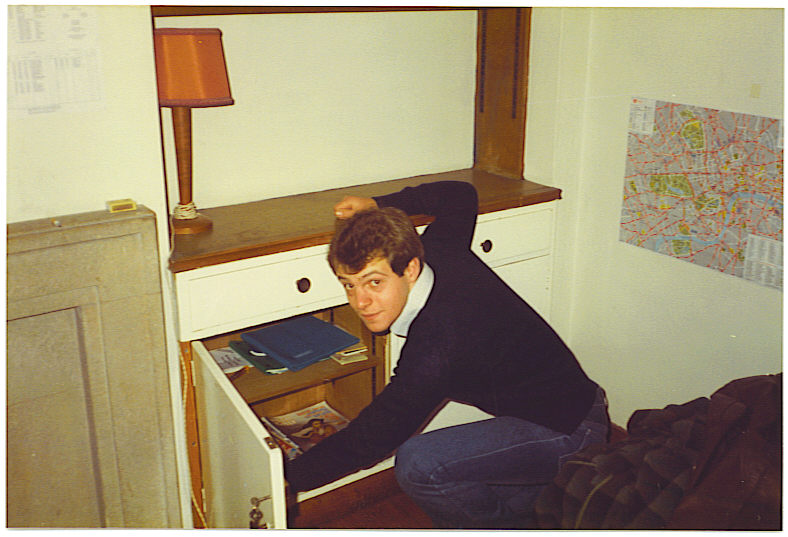 Tim is rifling through a cupboard in his student room.