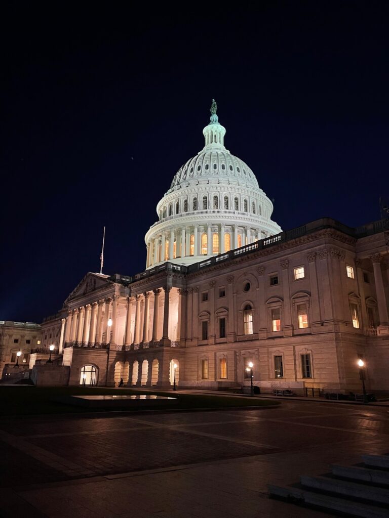 The Capitol dome glows white against a dark sky.