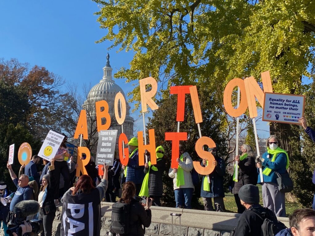 Protestors hold up individual letters spelling 'ABORTION RIGHTS'. Others hold signs. One reads 'Equality for ALL human beings, no matter their age, race or sexuality'.