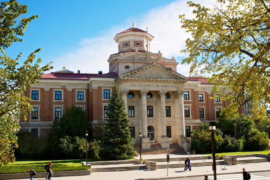 University of Manitoba - a large red brick building with white columns atthe front. It is surrounded by trees.